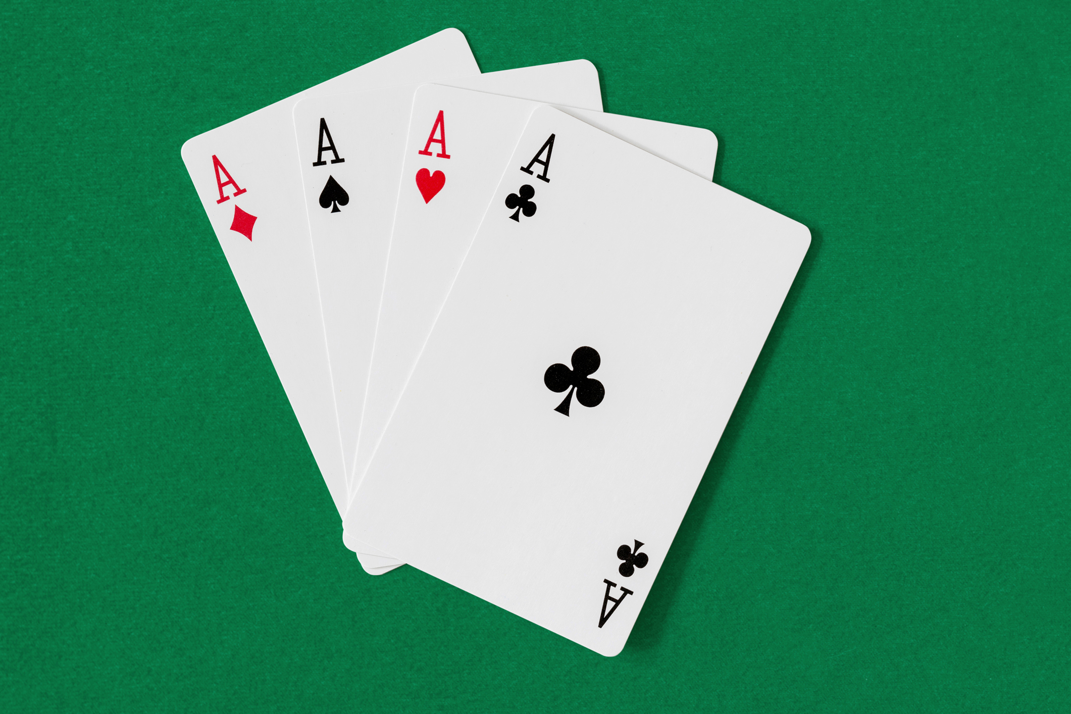 Four aces displayed on a green felt surface.