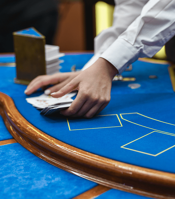 A dealer handling cards at a casino blackjack table.