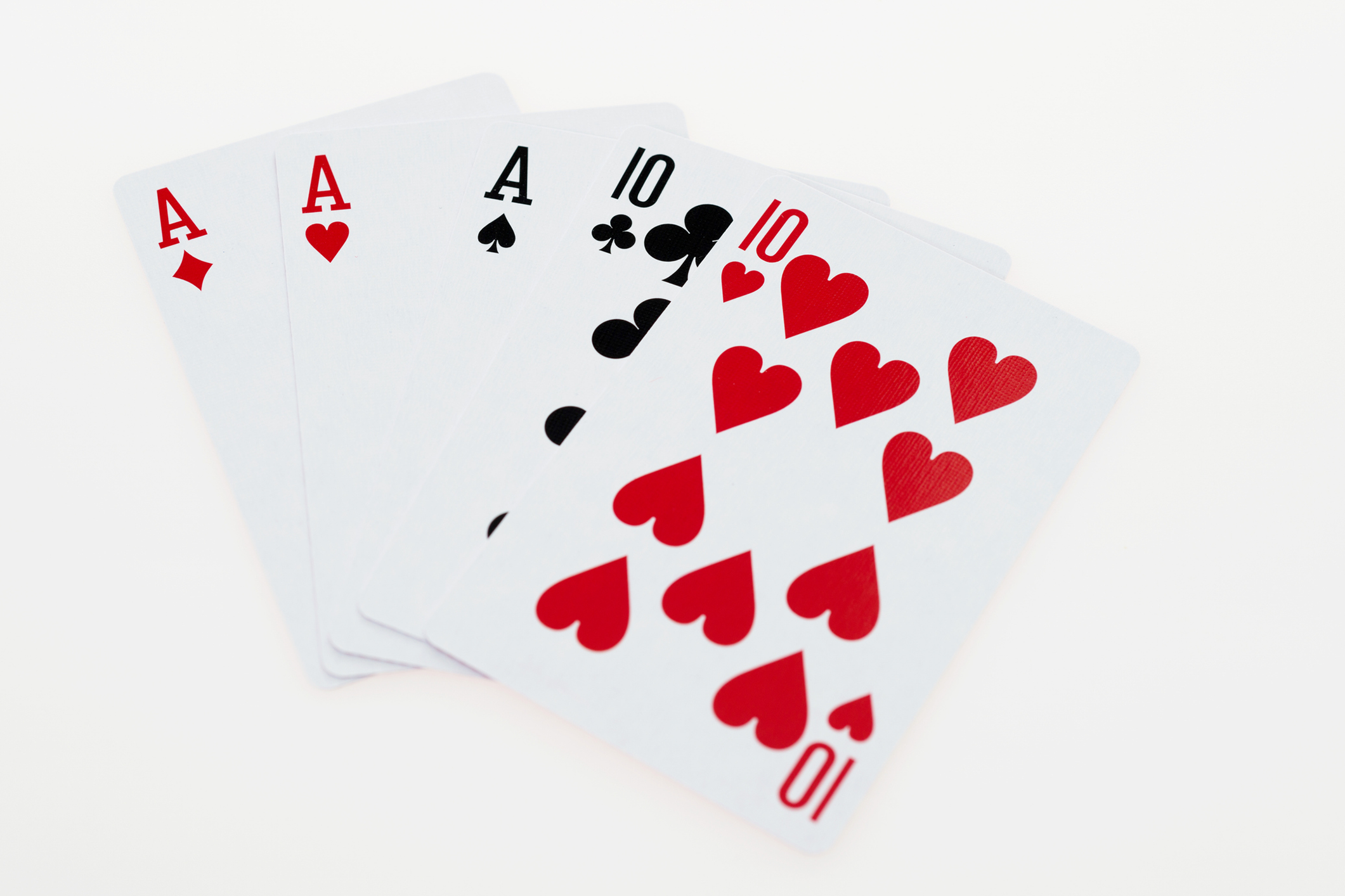 A close-up of playing cards showing two aces and three tens.