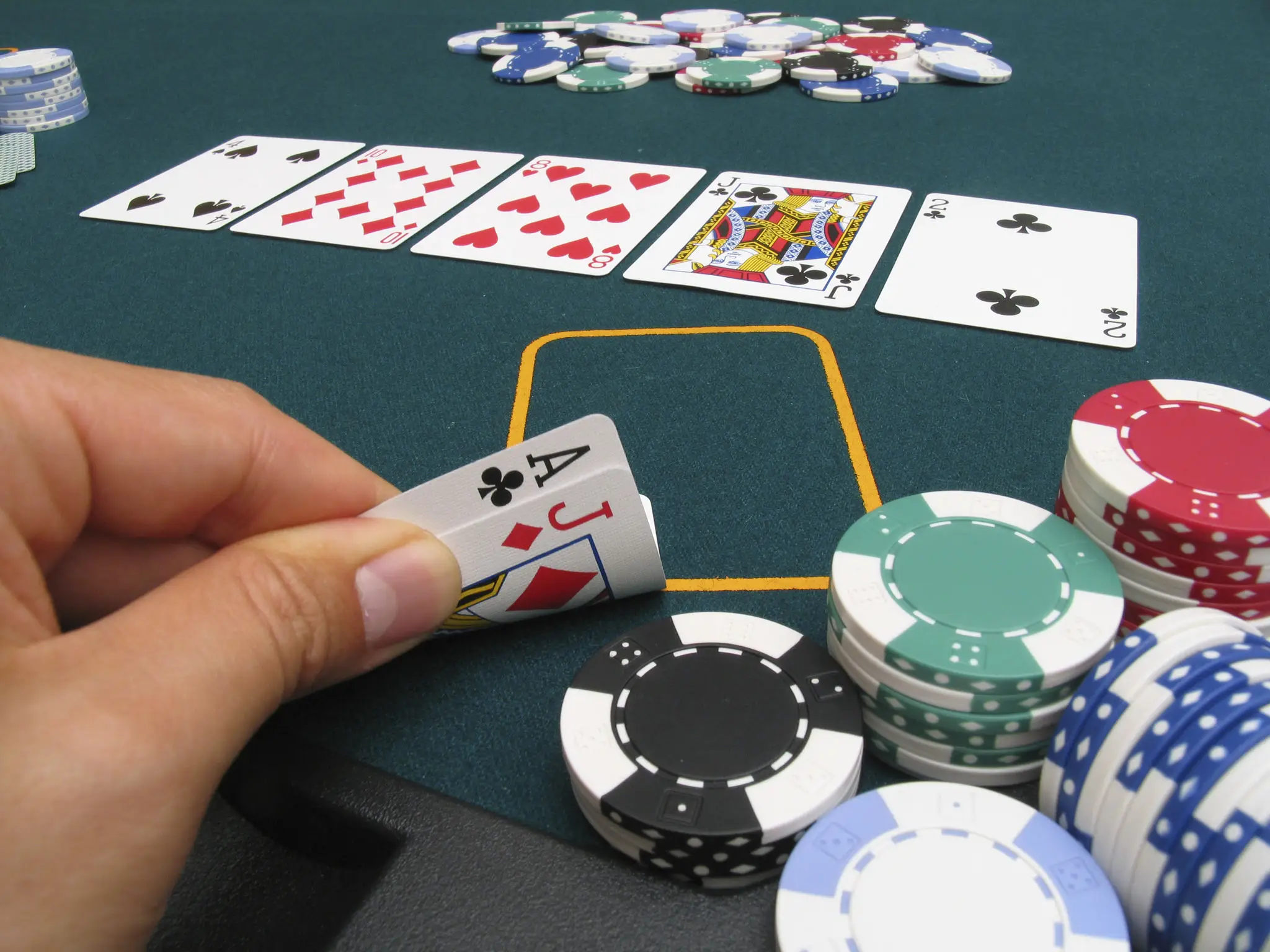 A player reveals a blackjack with an ace and a queen at a casino table.